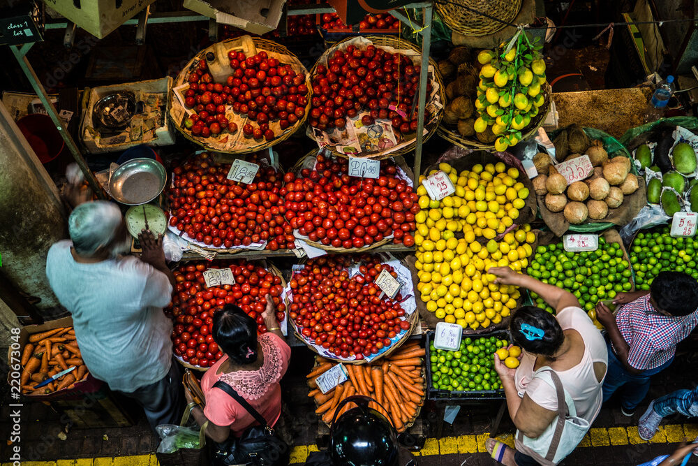 people buying food, fruit and vegetables at a stall in traditional central market in Port Louis, Mauritius | ROOTSMRU LTD